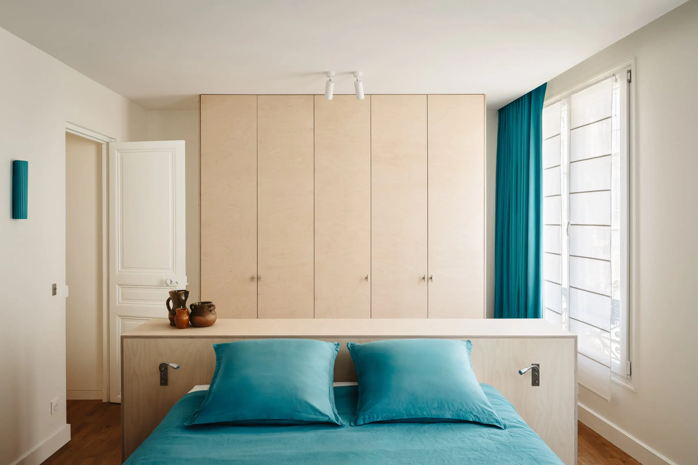 Chambre avec tête de lit en bois et linge de lit turquoise