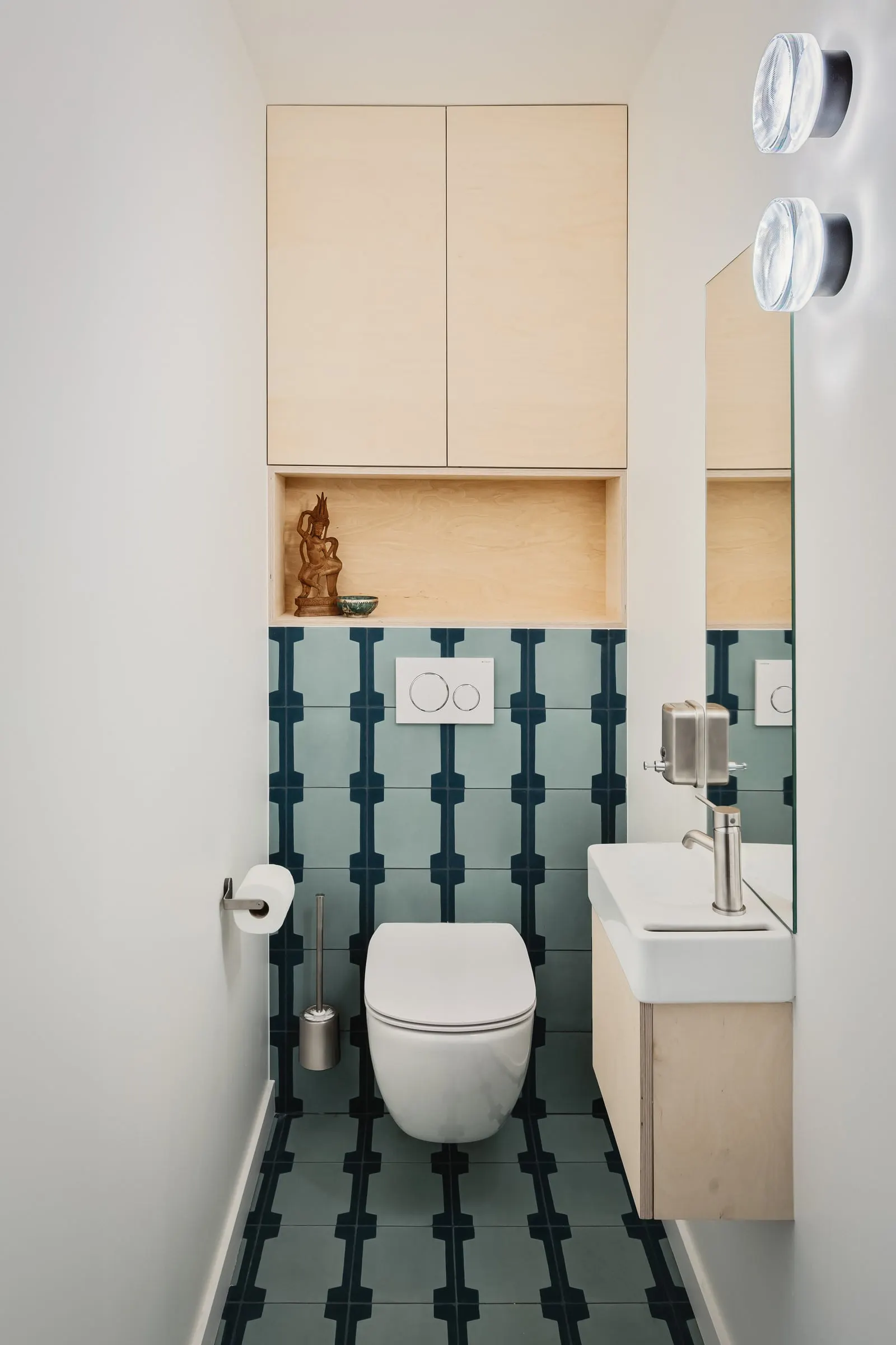 Toilettes au carrelage graphique bleu et rangement en bouleau