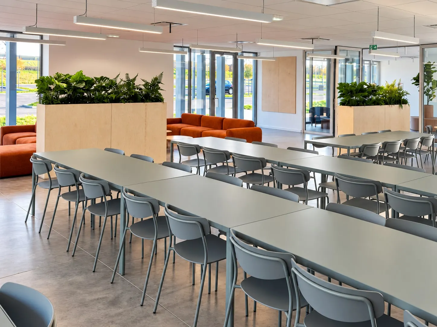 Grandes tables de cafétéria grises et chaises, jardinières hautes en bois
