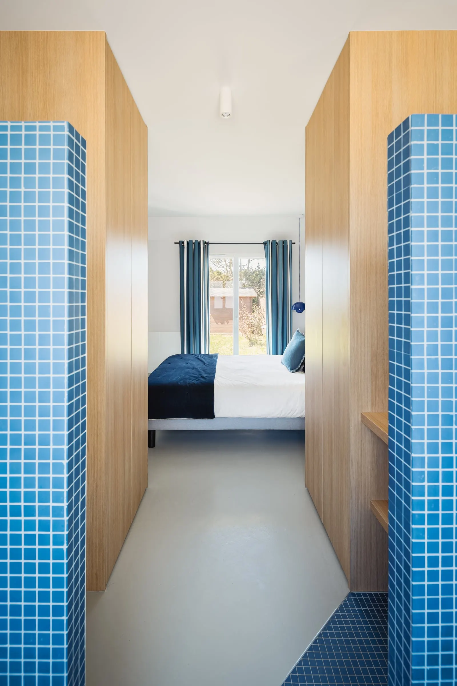 Passage entre deux murs en mosaïque bleue vers la chambre