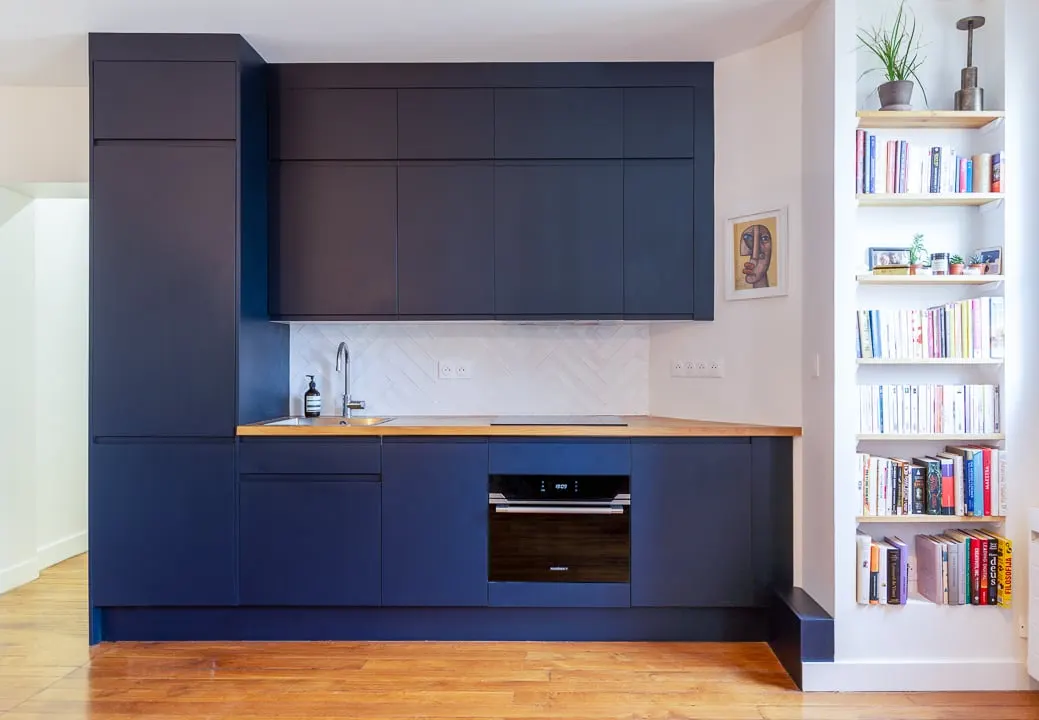 Cuisine bleu nuit avec plan de travail en bois et bibliothèque intégrée