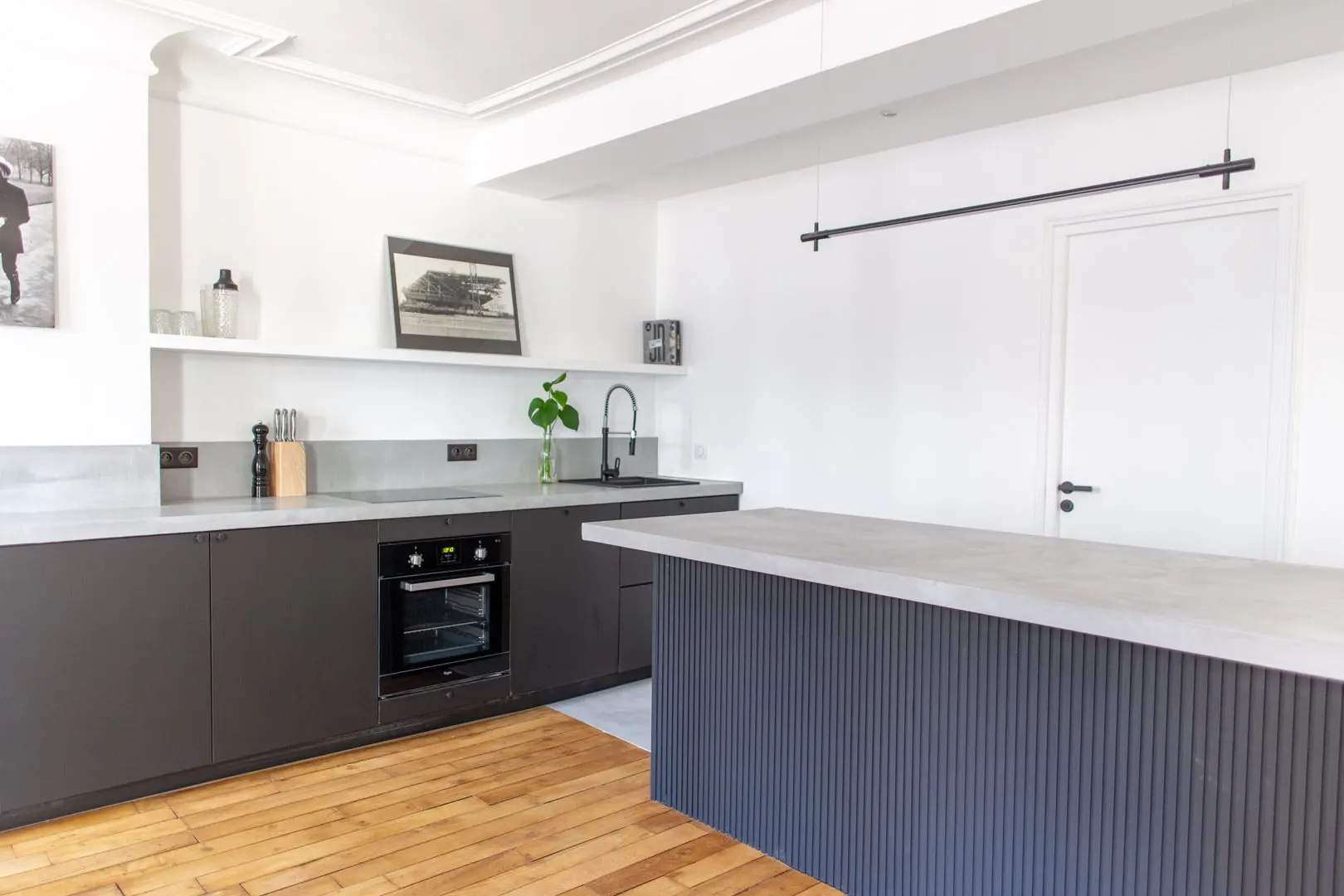 Cuisine aux façades noires et îlot au plateau en béton ciré