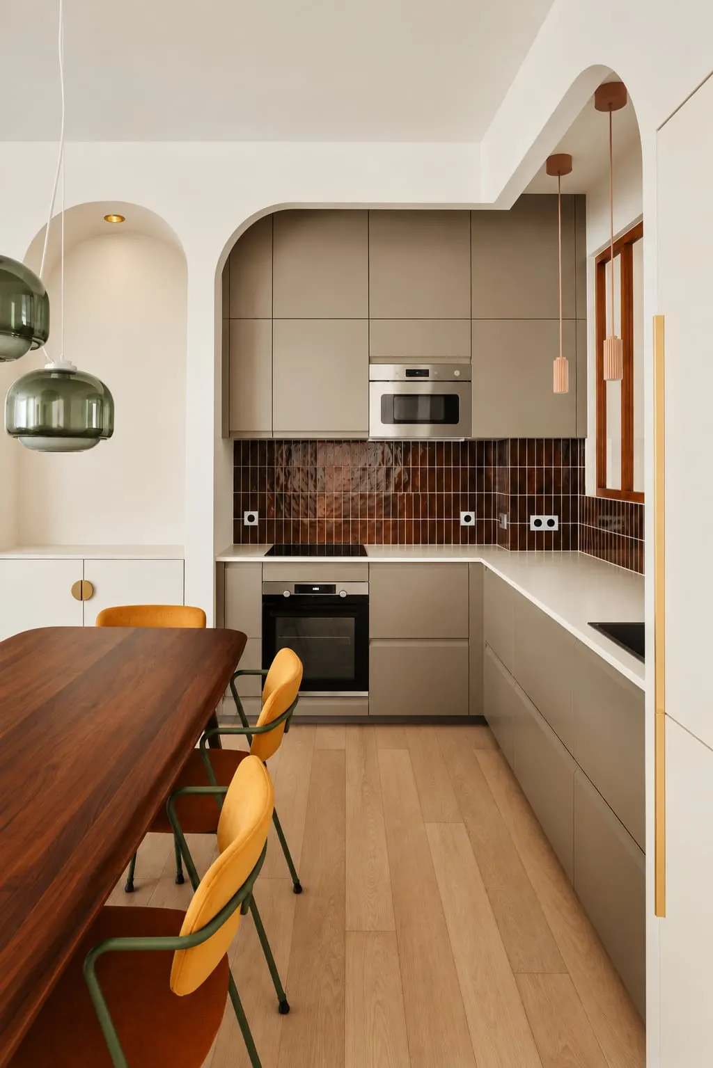 Cuisine de l’appartement Lucas, façades grège, crédence brune et arches blanches