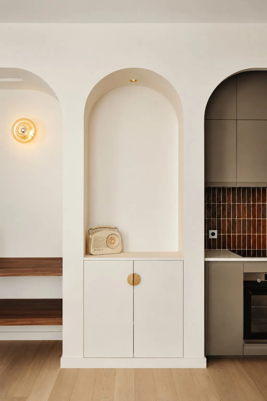 Niche en arche dans le séjour avec rangement bas et poignée dorée