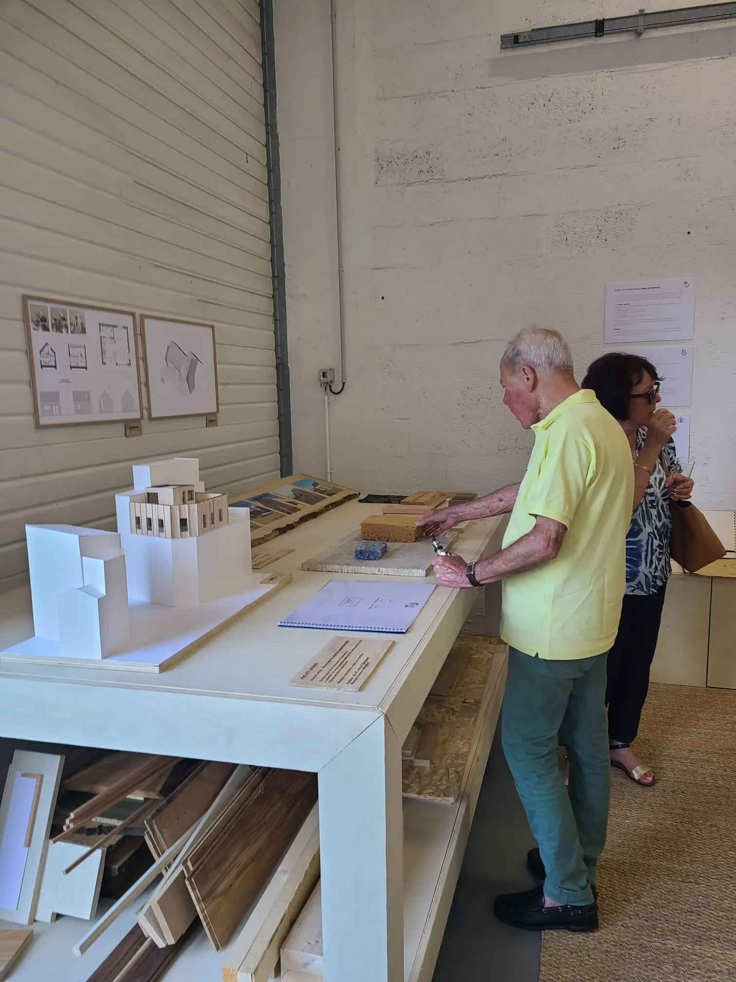 Visiteurs devant la maquette du projet Arago et les plans exposés sur l’établi