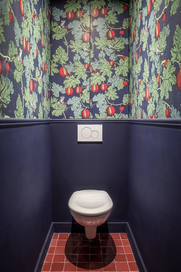 Toilettes au papier peint fleuri et soubassement bleu nuit